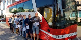 Grupa krwiodawców stojąca przed biało-czerwonym autobusem PCK