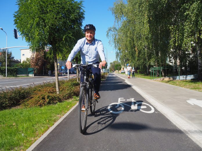 Na zdjęciu Daniel Putkiewicz Burmistrz Miasta i Gminy Piaseczno jadący rowerem po ścieżce rowerowej przy ul. Powstańców Warszawy w Piasecznie, na głowie ma kask.
