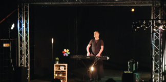 Czesław Śpiewa Solo Act / Muzyczny Stand Up. Na zdjęciu Czesław Mozil stoi na scenie i gra na syntezatorze.