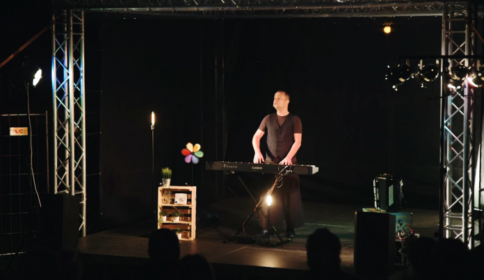 Czesław Mozil w Józefosławiu Czesław Śpiewa Solo Act / Muzyczny Stand Up. Na zdjęciu Czesław Mozil stoi na scenie i gra na syntezatorze.