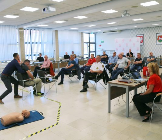 Szkolenia Strażników Miejskich. Na zdjęciu osoby biorące udział w szkoleniu na sali konferencyjnej, które oglądają praktyczny pokaz wyciągania rannej osoby z samochodu.