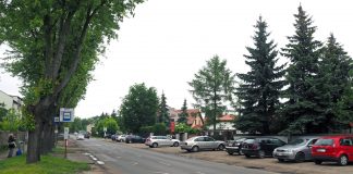 Rozbudowa drogi wojewódzkiej nr 722 ul. Księcia Janusza I Starego w Piasecznie. Na zdjęciu ulica, która będzie remontowana. Na poboczu stoją samochody.