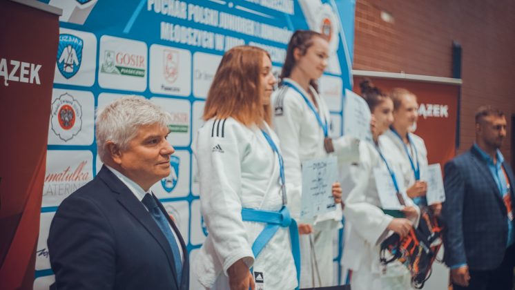 Na zdjęciu trzy uczestniczki stojące na podium, obok nich dwóch mężczyzn, którzy rozdawali medale.