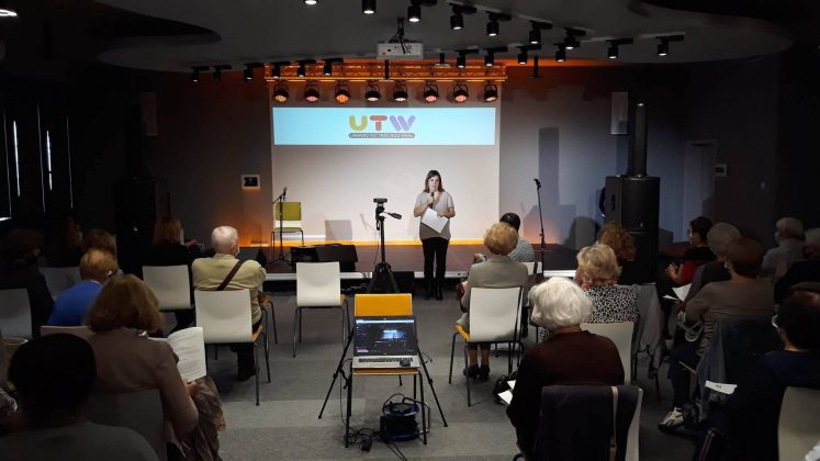 Inauguracja roku akademickiego UTW 2020/2021. Na zdjęciu koordynatorka UTW Joanna Samojlik, która przemawia do zebranych osób na sali widowiskowej w CEM Piaseczno.