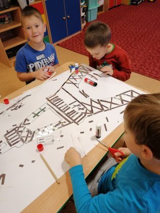 Zdjęcie. Kulinarne Podróże po Świecie w Nefrytowym Zakątku. Na zdjęciu trzech chłopców wykonuje pracę plastyczną- wyklejają wieżę Eiffla.