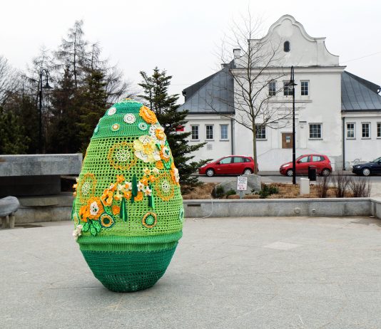 Ilustracja. Wielkanocna pisanka na skwerze Kisiela w Piasecznie, w tle budynek Biura Promocji i Kultury UMiG Piaseczno oraz Centrum Kultury w Piasecznie
