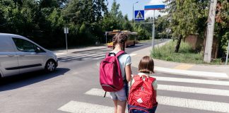 Bezpieczna droga do szkoły. Na zdjęciu dzieci z plecakami idące do szkoły po pasach dla pieszych.