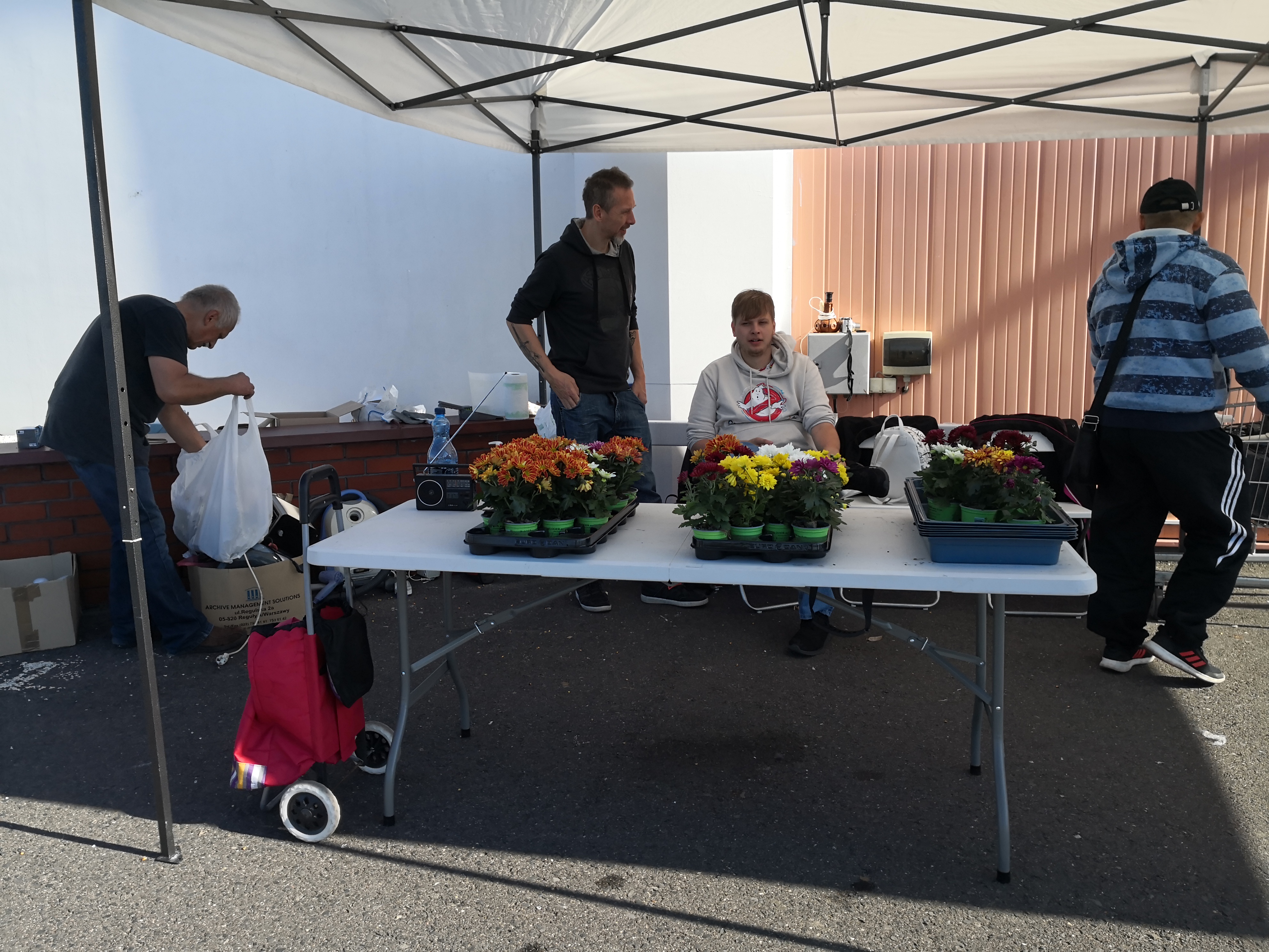 Kwiatek za elektrośmieci. Na zdjęciu organizatorzy akcji przy stoliku z kwiatami doniczkowymi.