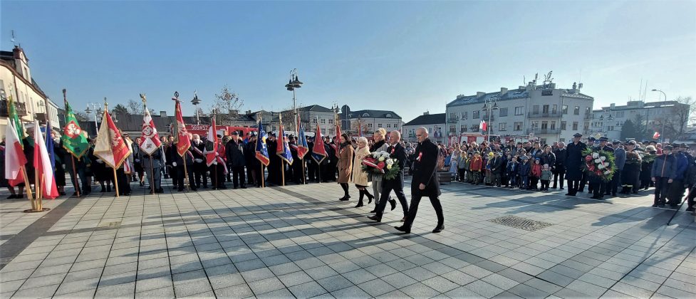 Dzień Niepodległości 2021 w Piasecznie. Na zdjęciu burmistrz Daniel Putkiewicz i radni idą, by złożyć wieniec pod tablica upamiętniającą Marszałka Piłsudskiego przy ratuszu.