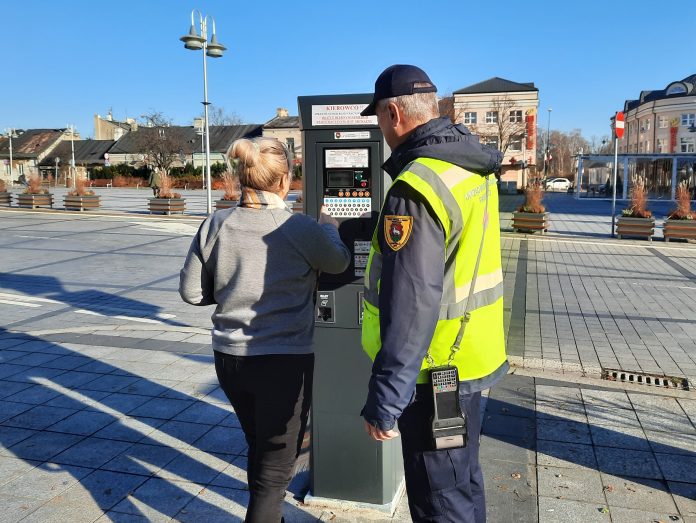 Obrażanie kontrolerów czy strażników miejskich może sporo kosztować. na zdjęciu kontroler pomagający kobiecie kupić bilet parkingowy w parkomacie przy pl. Piłsudskiego.