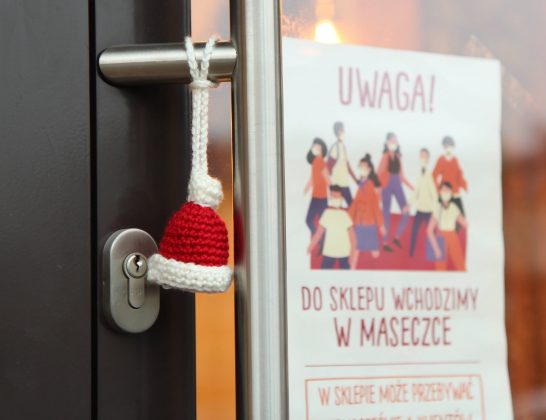 Mikołajkowe czapeczki od "Zamotanych w Piasecznie" ozdobiły miasto. Na zdjęciu czapeczka na klamce piekarni.