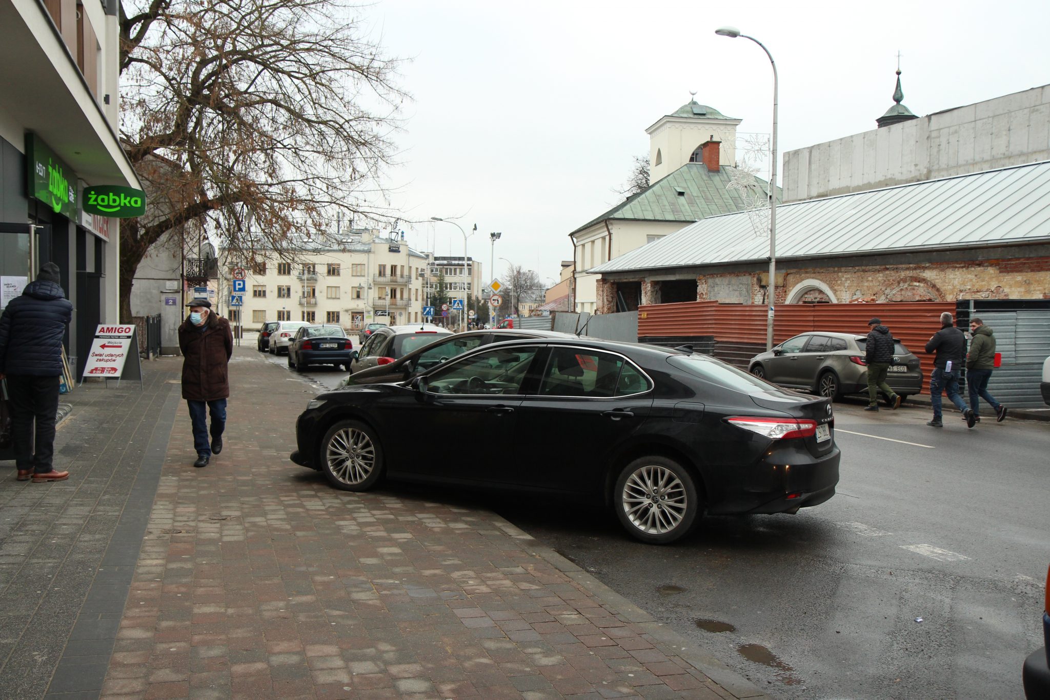 Gmina planuje przebudowę kolejnego odcinka głównej arterii miasta. na zdjęciu samochody parkujące na chodniku na ul. Puławskiej.