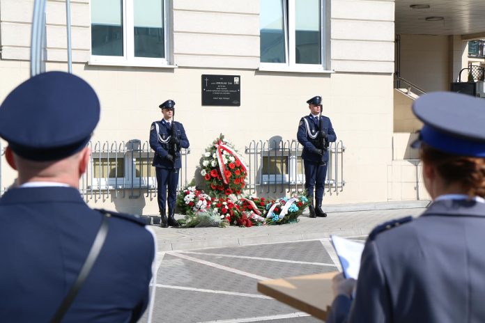 policjanci na warcie przy tablicy pamiatkowej umieszczonej na buudynku policji
