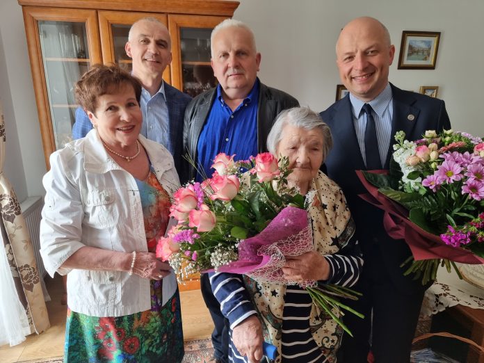 100-latka z Żabieńca. na zdjęciu Jubilatka z kwiatami, Burmistrz i inni goście