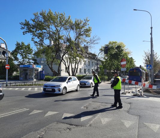 Utrudnienia drogowe związane z inwestycjami powiatu. Na zdjeciu skrzyżowanie, strażnicy miejscy, samochody.
