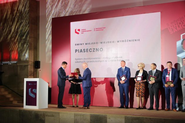 grupa samorządowców na scenie. burmistrz Piaseczna w stroju galowym odbiera nagrodę.