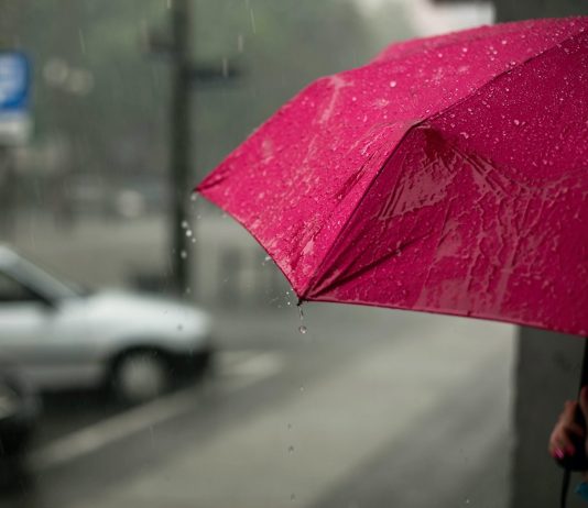 Ostrzeżenie przezd deszczem. Na zdjęciu różowa parasolka.