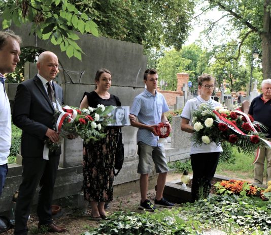 groby powstańców w Piasecznie. Burmistrz Daniel Putkiewicz oraz 5 innych osób ze zniczami i kwiatami na cmentarzu.