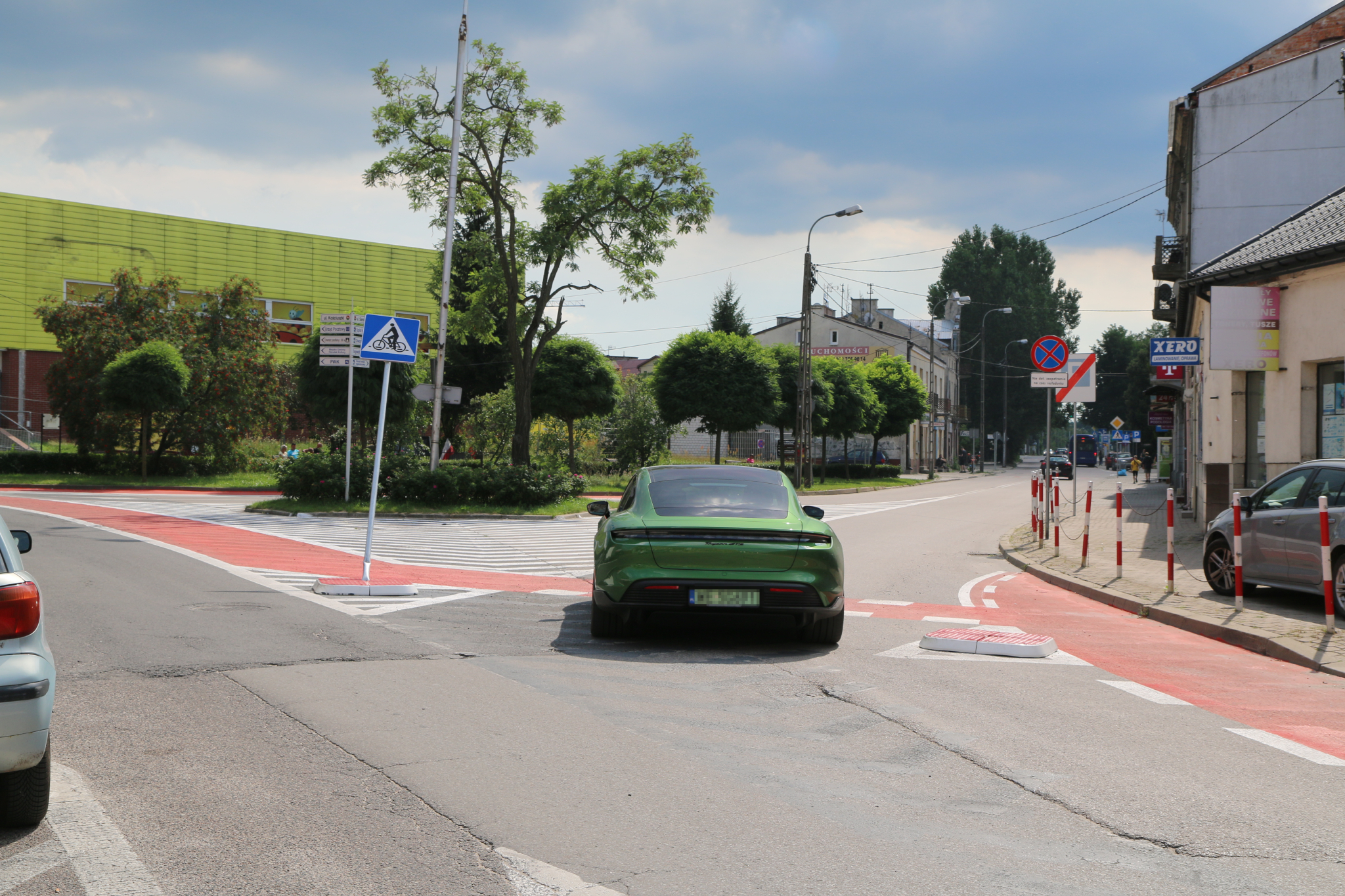 pas rowerowy Kościuszki. na zdjeciu pas rowerowy, jezdnia i zielony samochód.