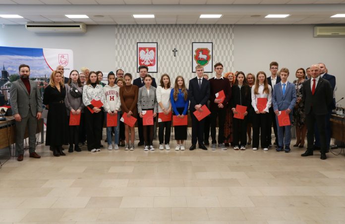 Stypendia Burmistrza Miasta i Gminy Piaseczno wręczone Stypendyści Burmistrza. Na zdjeciu grupa kilkunastu uczniów oraz nauczyciele i rodzice, a także burmistrzowie.