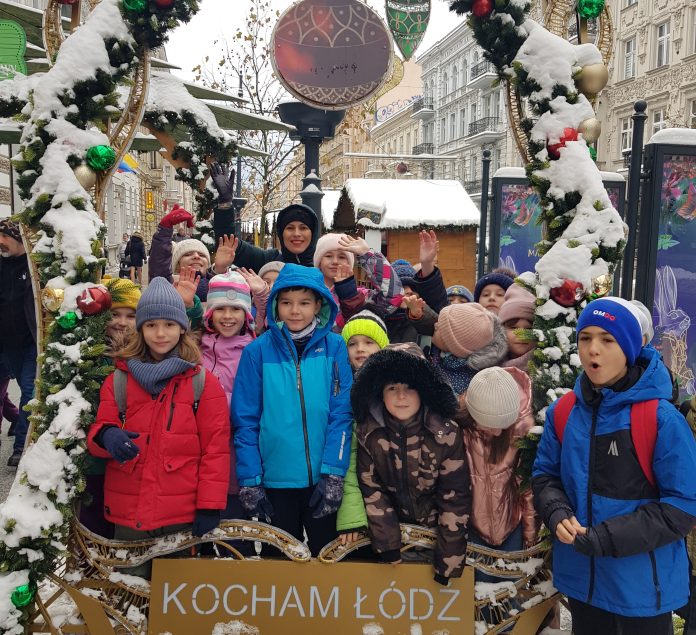 Uczniowie na wycieczce w ramach programu “Poznaj Polskę” grupa dzieci z nauczycielką pozują wspólnie na wycieczce w zimowej scenerii
