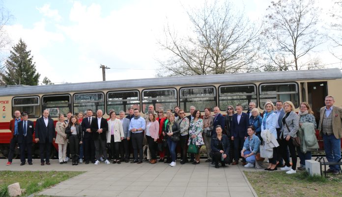 Wizyta z Metropolii zdjecie grupowe , w tle wagon kolejki wąskotorowej