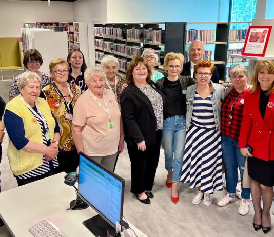 Otwarcie biblioteki w Przystani pod Klonami. Na zdjęciu grupa osób w pomieszczeniu biblioteki.