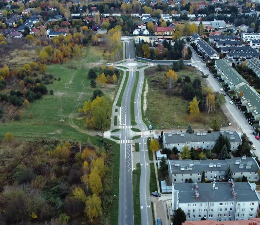 Urbanistów bis - widok drogi z lotu ptaka, obok zabudowania oraz teren zielony.