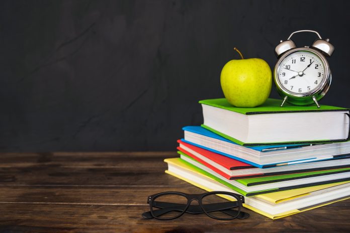 Życzenia dla Ósmoklasistów na grafice książki, jabłko, okulary, budzik