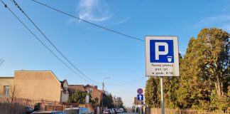 zdjecie ulicy z samochodami i znakiem "parking"