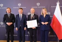 trzech mężczyzn i kobieta, obok polska flaga