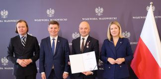 trzech mężczyzn i kobieta, obok polska flaga