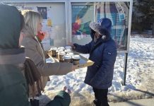 MGOPS w Piasecznie oferuje gorącą herbatę i ciepłą zupę potrzebującym kobieta z tacą pełną kubków herbaty i druga biorąca kubek