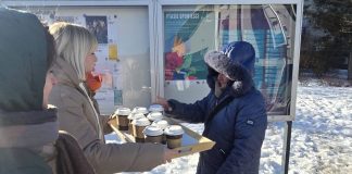 kobieta z tacą pełną kubków herbaty i druga biorąca kubek