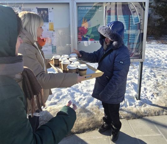 kobieta z tacą pełną kubków herbaty i druga biorąca kubek