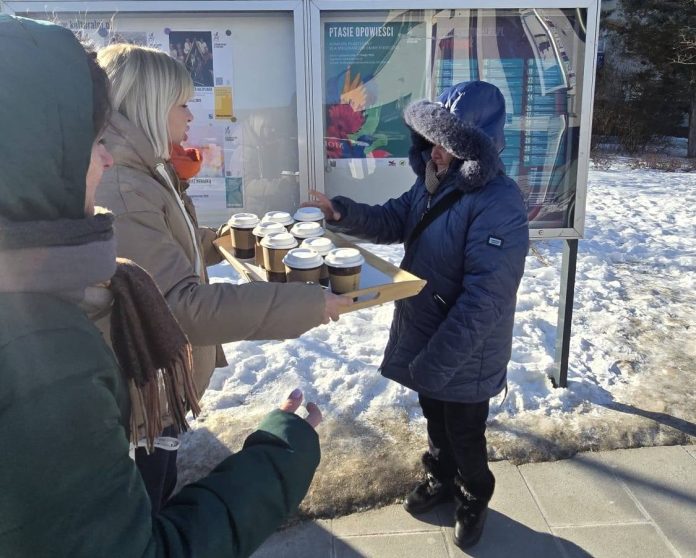 kobieta z tacą pełną kubków herbaty i druga biorąca kubek