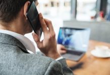 Mężczyzna przy laptopie, rozmawiający przez telefon komórkowy