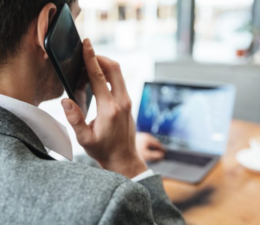 Mężczyzna przy laptopie, rozmawiający przez telefon komórkowy