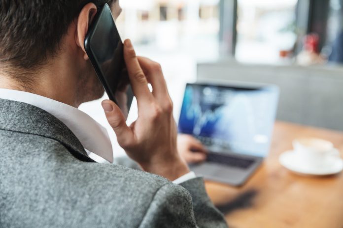 Mężczyzna przy laptopie, rozmawiający przez telefon komórkowy