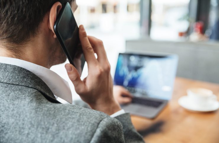 Mężczyzna przy laptopie, rozmawiający przez telefon komórkowy