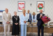 grupa osób, burmistrz trzyma bukiet i mówi do mikrofonu