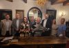 grupa 8 osób, artysta trzyma w ręku rzeźbę ryby