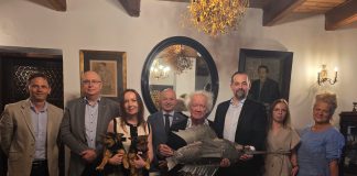 grupa 8 osób, artysta trzyma w ręku rzeźbę ryby
