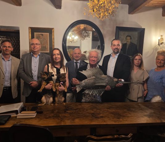 grupa 8 osób, artysta trzyma w ręku rzeźbę ryby