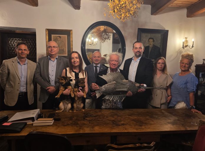 grupa 8 osób, artysta trzyma w ręku rzeźbę ryby